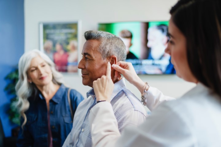 audiologist fitting hearing aid in patient's ear